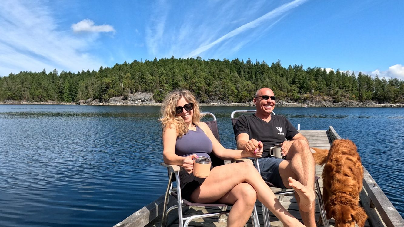 Jared and Ang relaxing on a dock with their golden retriever