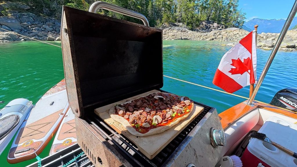 Homemade sourdough pizza with deer pepperoni cooking on the boat barbecue